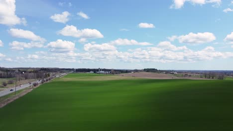 aerial of farmland fields in rural ontario with lush green crops and rolling hills with blue sky