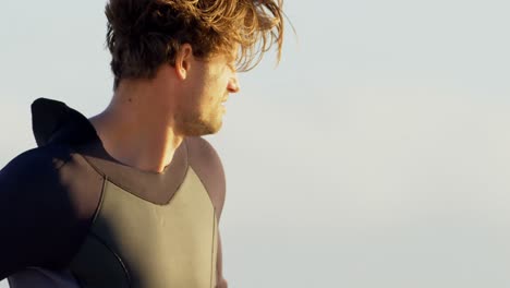 surfista masculino con traje de neopreno en la playa 4k