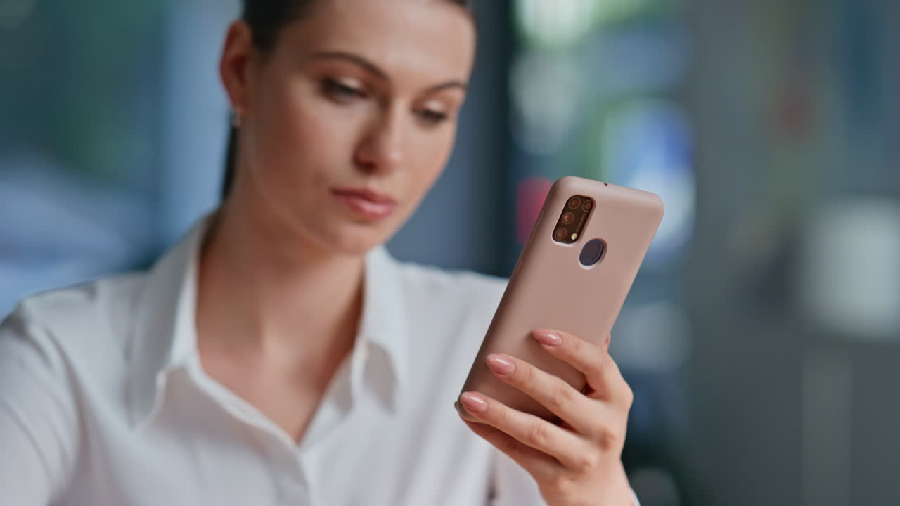 Dettaglio di una donna sicura di sé che guarda lo schermo del cellulare leggendo un messaggio sul posto di lavoro