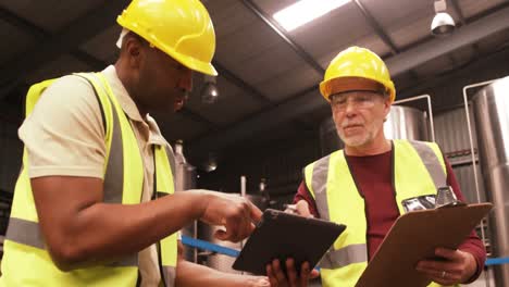 worker using digital tablet while writing on clipboard
