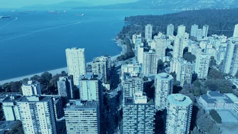 Vancouver-English-Bay-Davie-Street-post-modern-residential-aerial-drone-reveres-reveal-flyover-stunning-buildings-surrounding-Stanley-Park-flat-blue-water-with-freighter-shipping-boats-in-the-horizon