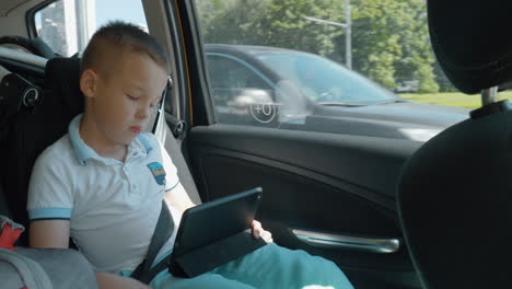 Niño-Aburrido-Viendo-Una-Película-En-La-Plataforma-Durante-El-Viaje-En-Coche.