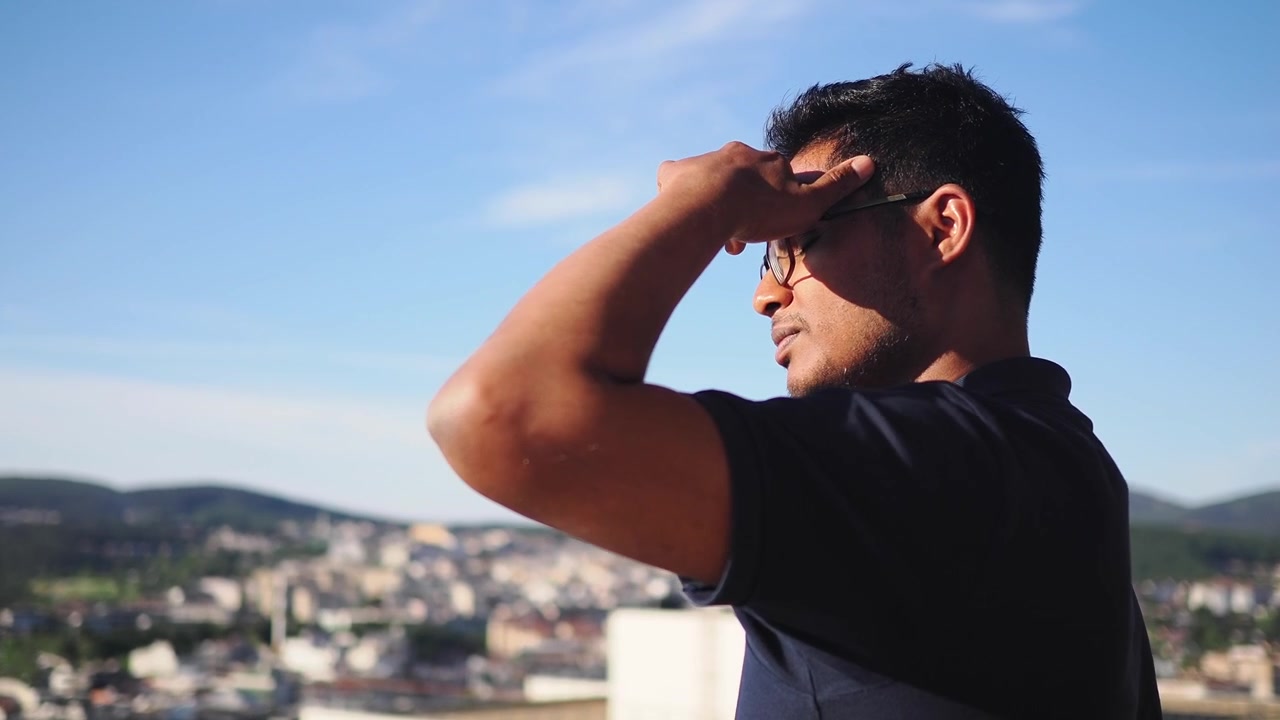 Young Man Looking at City View from Rooftop