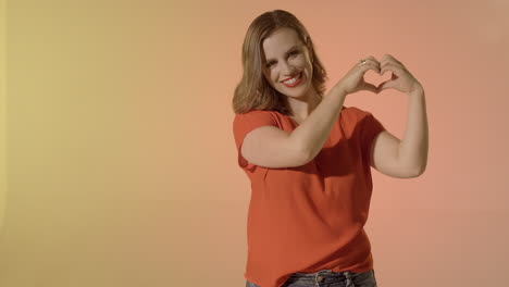 señora rubia hace un corazón con manos y sonrisas