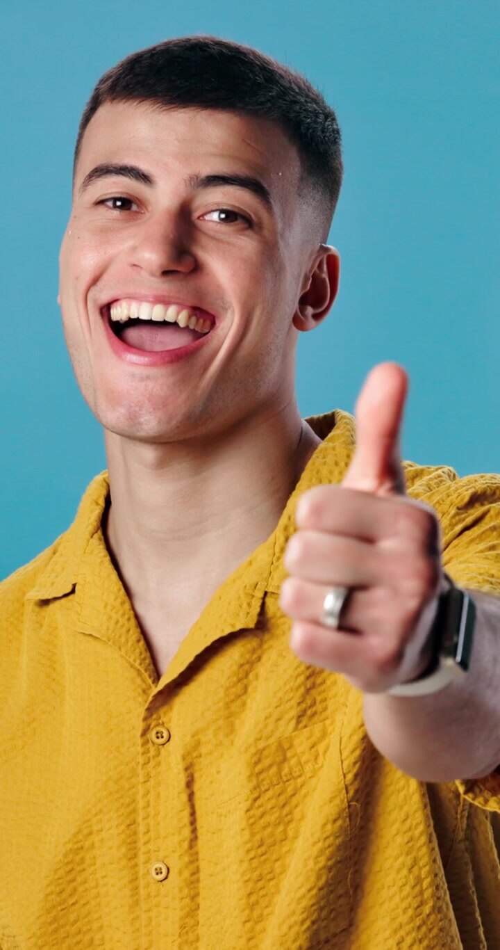 Giovane uomo felice che fa il gesto del pollice in su