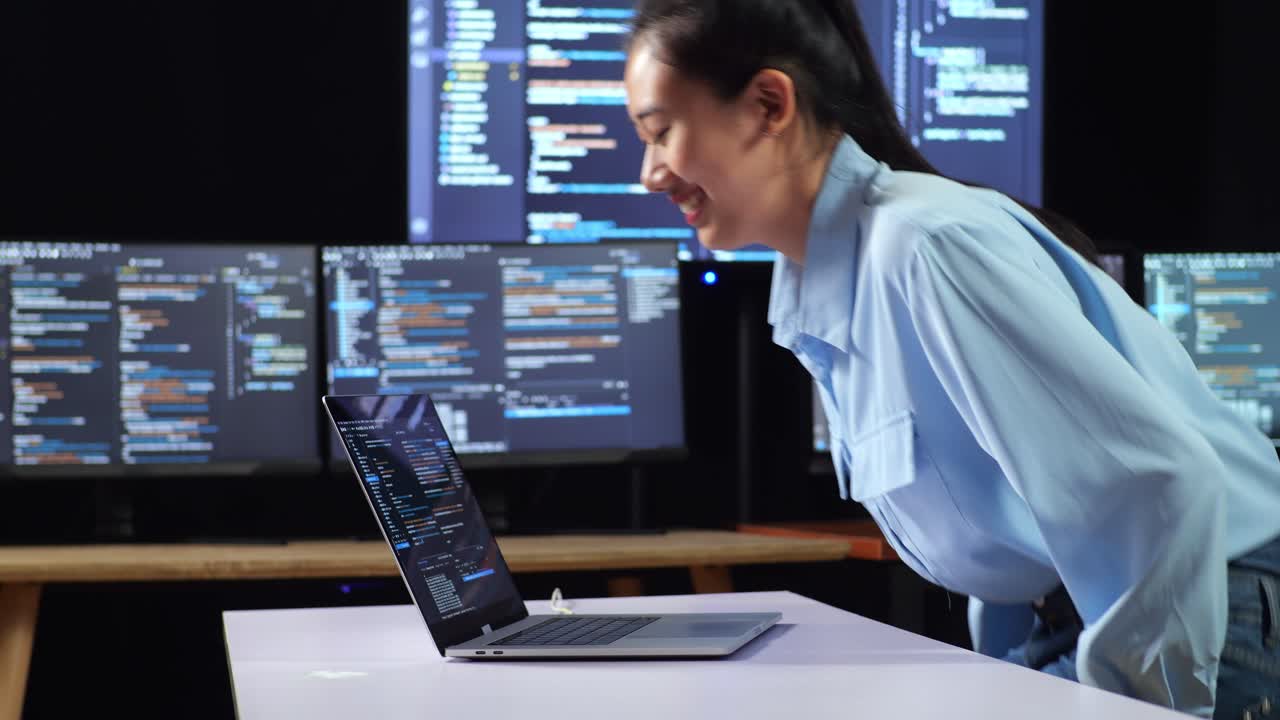 여러 모니터를 사용하여 노트북으로 코드를 작성하기 위해 작업 공간으로 들어가는 아시아 여성 프로그래머의 측면 시각 사무실의 터미널 창 데스크에서 데이터베이스를 보여줍니다.