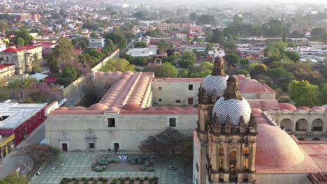 aerial view of santo domingo de guzman church and square in historic downtown of oaxaca city, mexico, revealing pull back drone shot