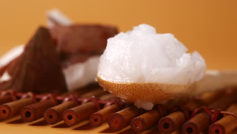 aceite de coco en una cuchara de madera en una alfombra de bambú