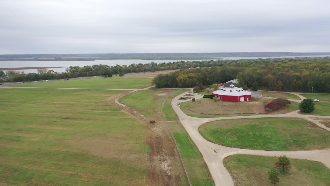 vista aérea de un patio de granja cubierto de hierba en illinois con un granero rojo y el río en el fondo