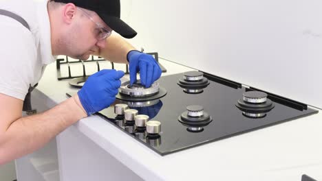 a young handyman is repairing a gas stove in the kitchen gas stove repair
