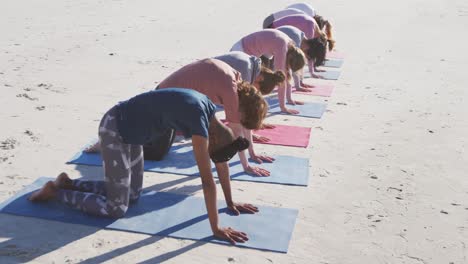 Multiethnische-Gruppe-Von-Frauen,-Die-Yoga-Position-Am-Strand-Und-Im-Hintergrund-Des-Blauen-Himmels-Machen