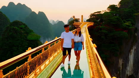 couple walks hand-in-hand on scenic glass bridge at sunset