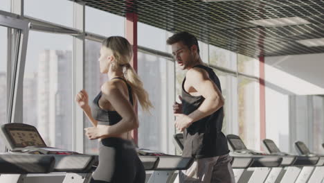 fitness couple running on treadmill machine in gym club together