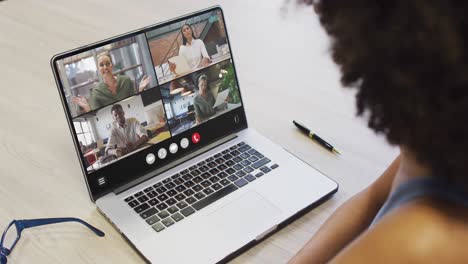 african american woman using laptop for video call, with diverse business colleagues on screen