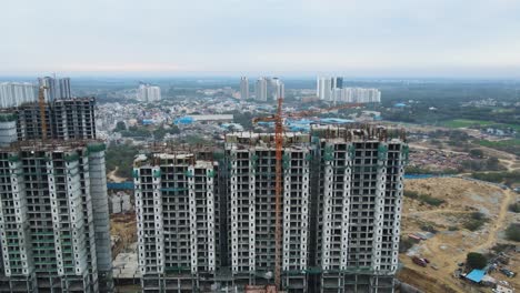 aerial drone shot showcasing the massive scale of an under-construction high-rise near dwarka expressway, with workers and machinery in motion.