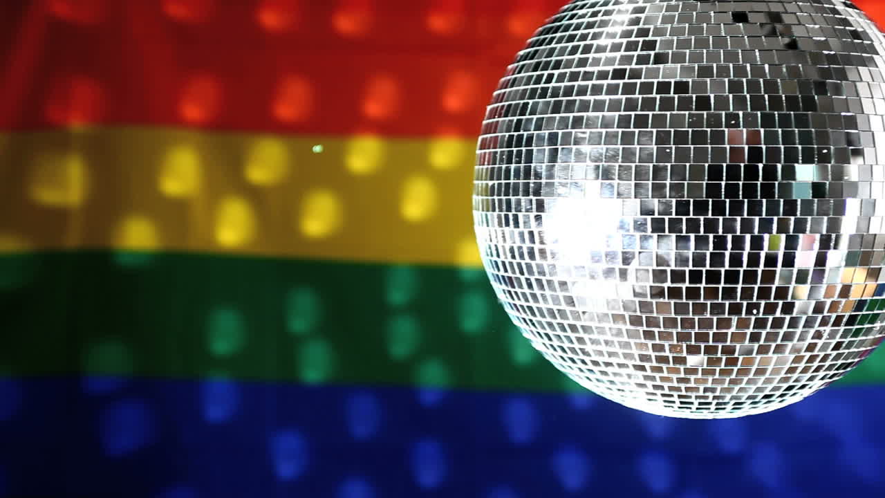 bola de discoteca girando contra la bandera del orgullo gay