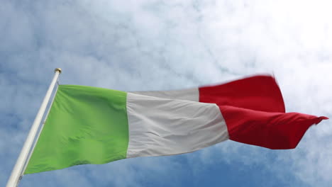 bandera italiana verde, blanca y roja ondeando en un fuerte viento con un cielo azul real y nubes en el fondo vistas desde abajo