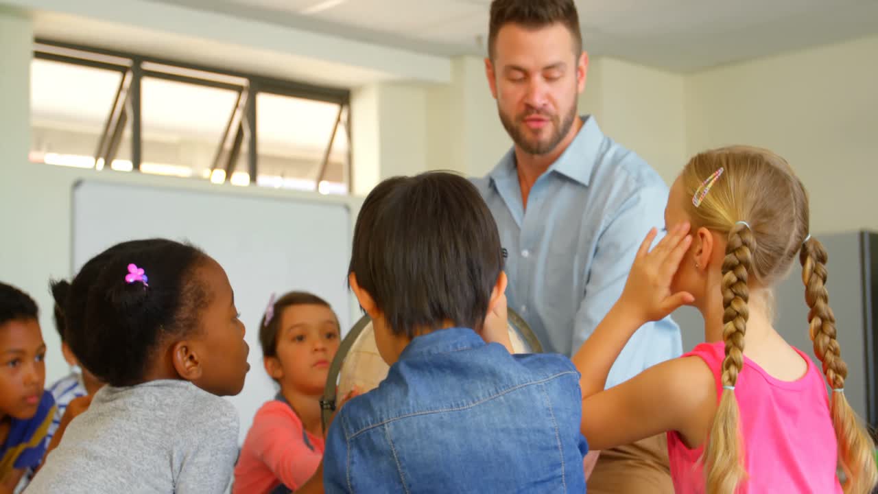 maestro masculino caucásico enseñando a sus hijos sobre el globo en el aula 4k