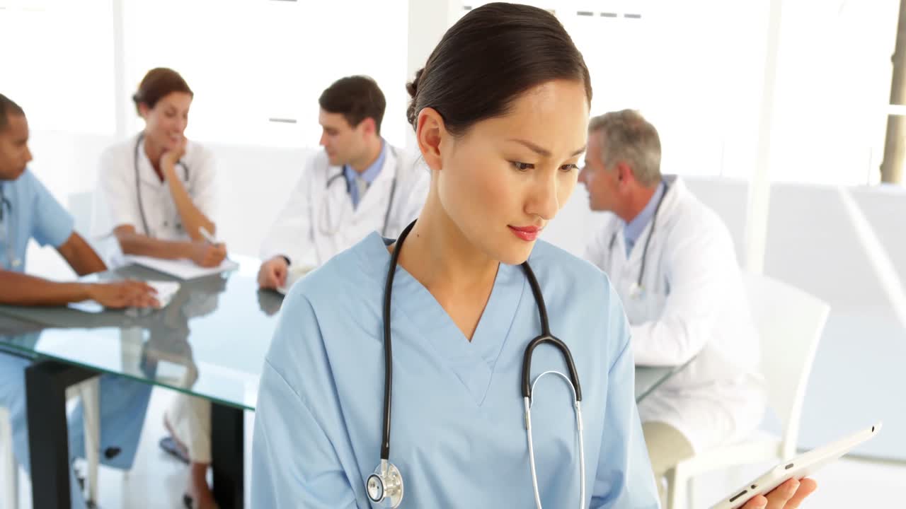 행복 한 간호사 는 직원 들 이 그녀의 뒤 에 있는 카메라 를 보고 있다