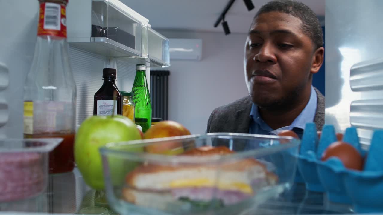 hombre buscando comida en el refrigerador por la noche