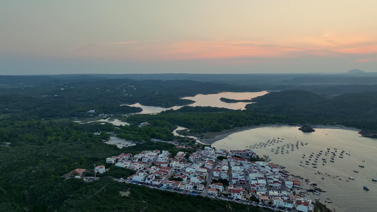 Drone shot backing out and rising while filming the amazing sunset over the beautiful and scenic nature of Menorca.