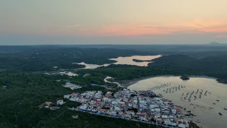 drone shot backing out and rising while filming the amazing sunset over the beautiful and scenic nature of menorca.