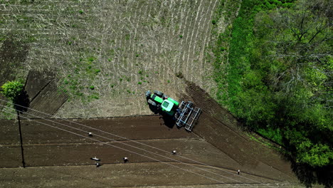 aerial view of chisel plough tractor carving furrows in fields, tilling soil