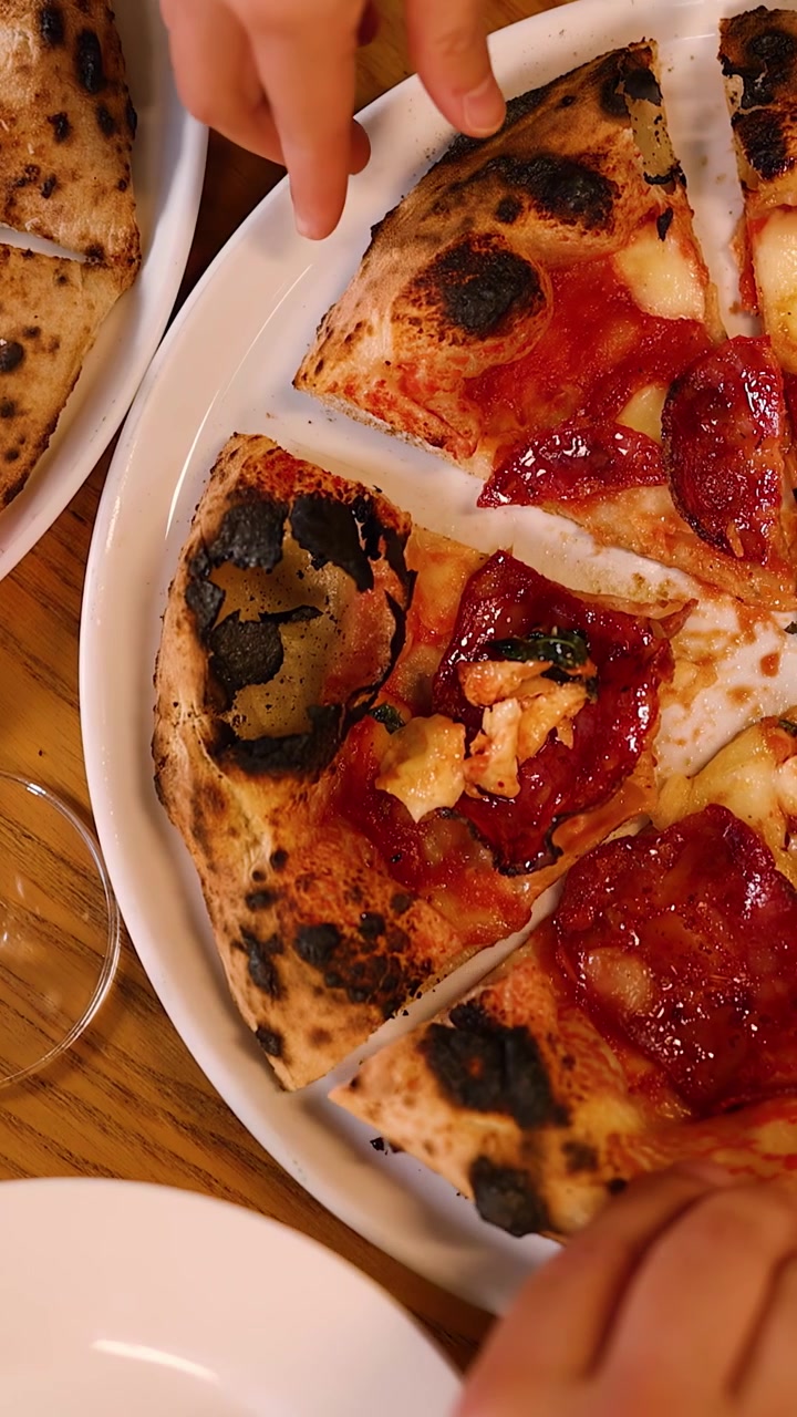 Ripresa dall'alto di persone che prendono fette di pizza fresca al pepperoni da un piatto bianco