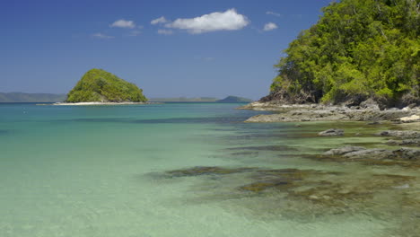 tropical paradise island landscape with clear turquoise water and rocky shore