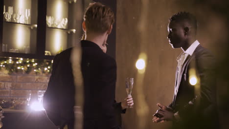 group friends wearing stylish clothes while talking and holding champagne glasses at new year's party 3