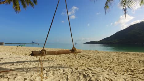 tranquila playa exótica con arena blanca bañada por un mar en calma en una isla tropical, balancín estático colgando del tronco de la palma en malasia