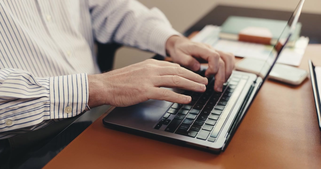 Empresário digitando em laptop na mesa do escritório