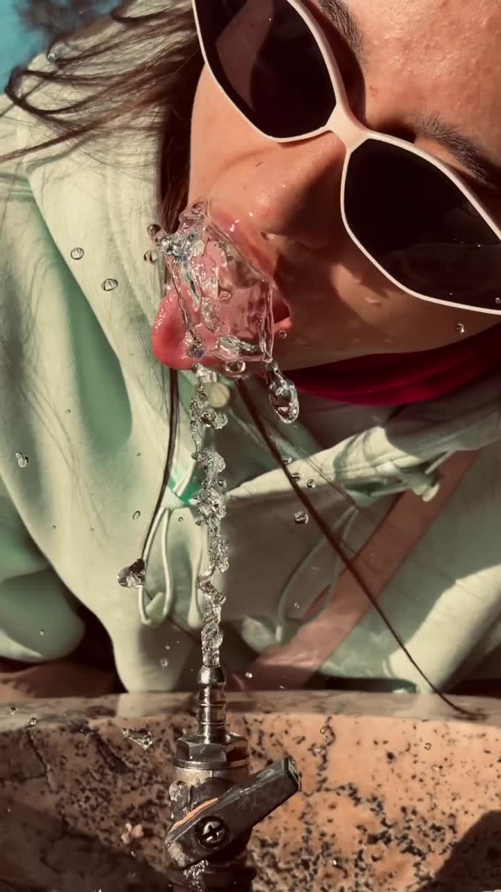 Donna che beve acqua rinfrescante da una fontana pubblica