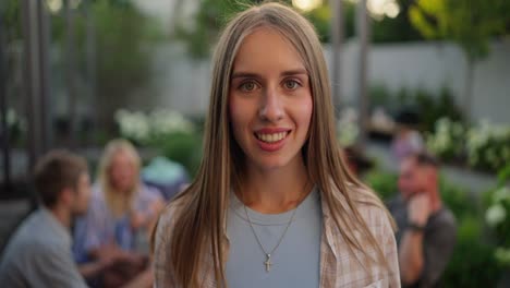 woman smiling at the camera while enjoying a party with friends