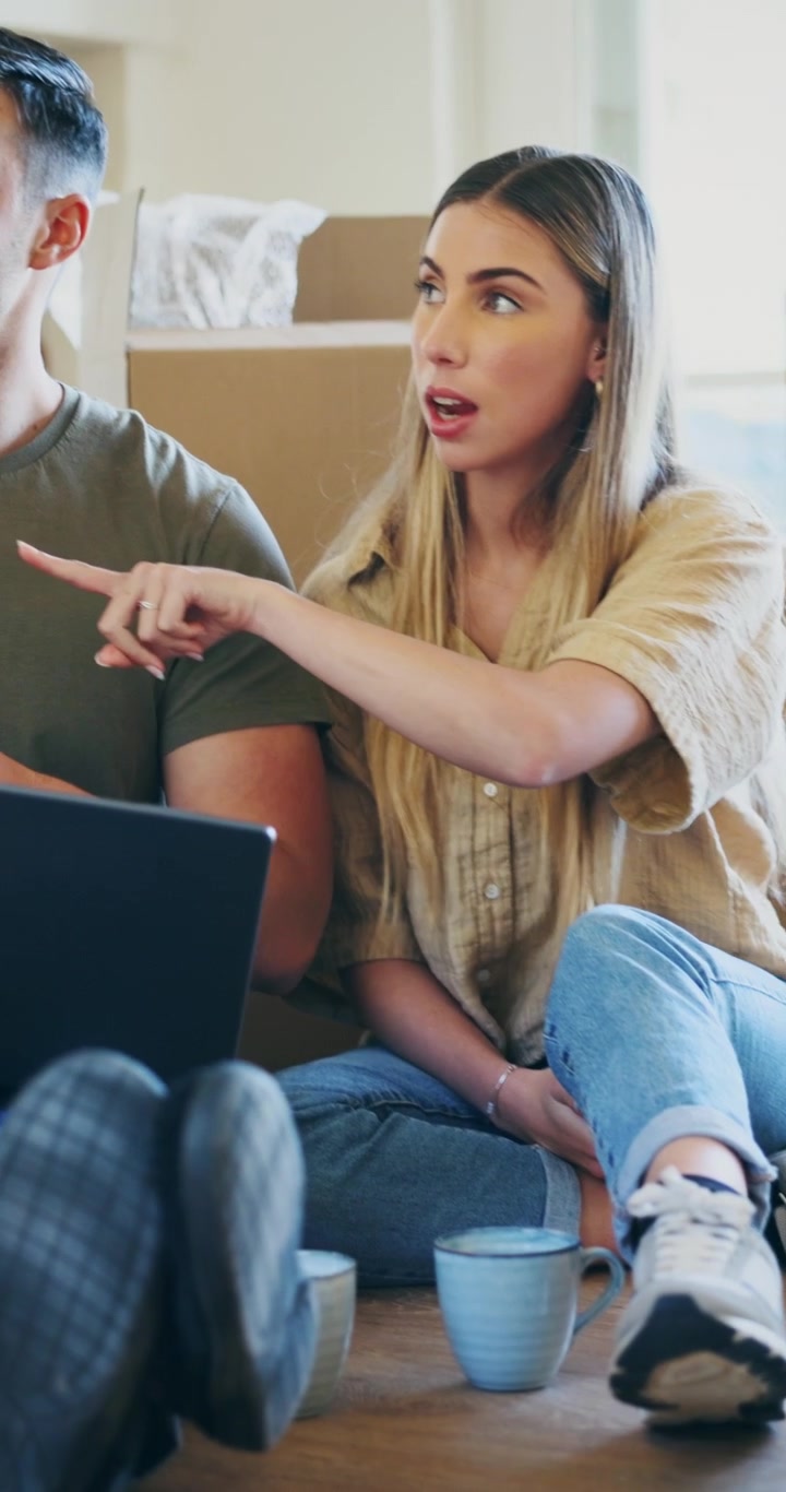 Young Couple Sitting on Floor Using Laptop in New Home