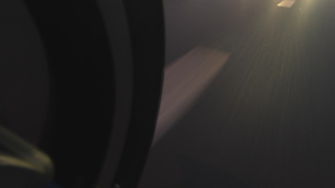 POV low angle camera on scooter motorcycle driving around city road sign traffic at night