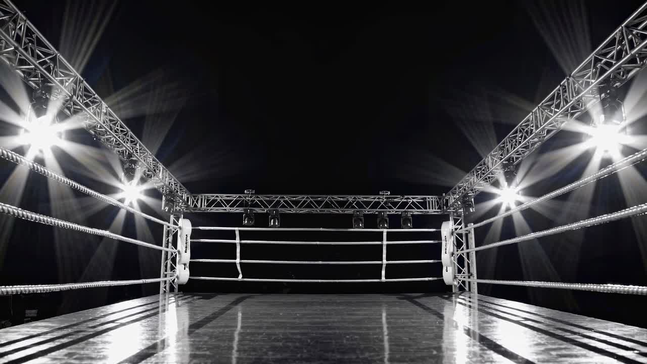 Dramatic low-angle shot of an empty boxing ring under bright lights, capturing a cinematic video