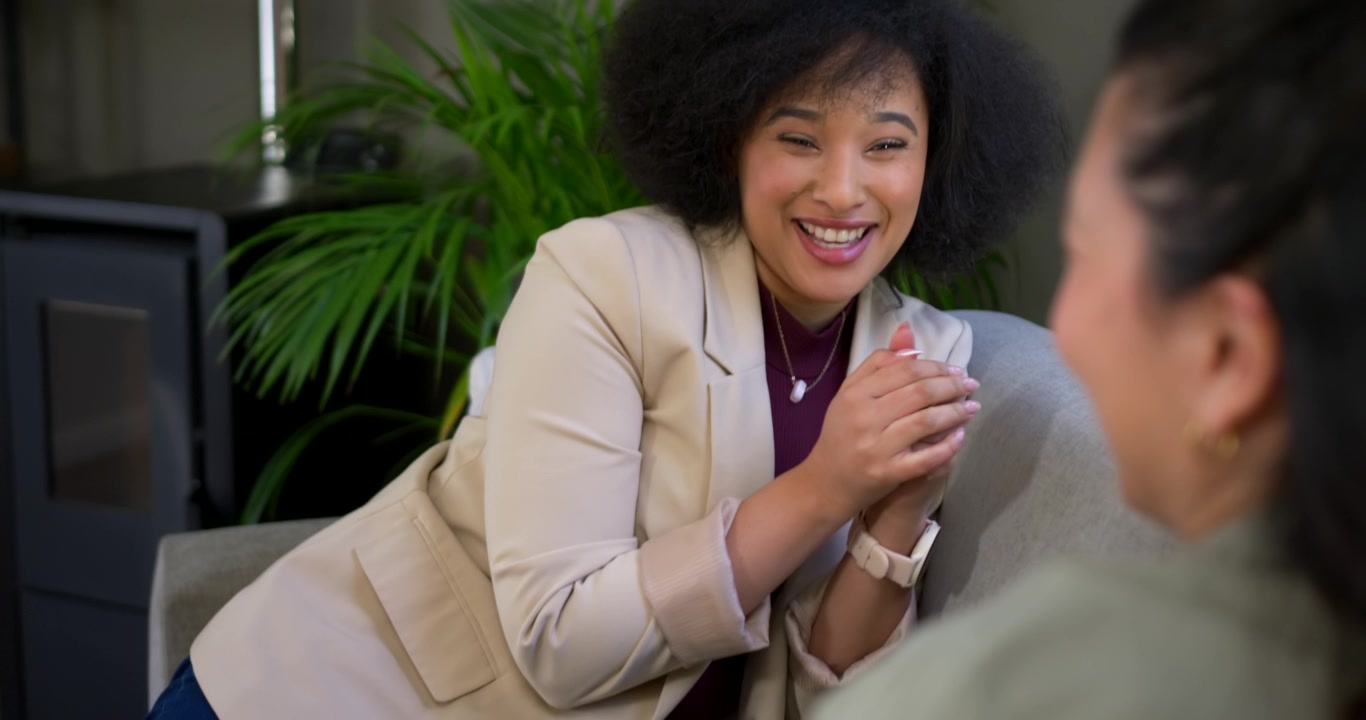 Diverse female duo, gesturing African American reacting to cue as Asian woman holding cup at lounge