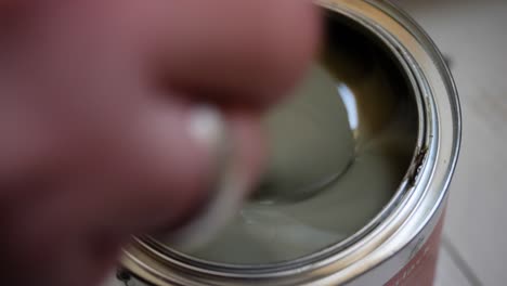 a female hand stirs paint in a paint can