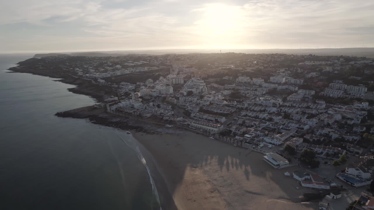 Landscape of sandy beach Praia Da Luz , Algarve. Golden sunset over town and Atlantic Ocean
