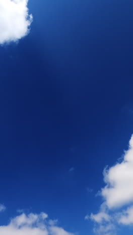 light white clouds floating quickly in the bright blue skies. fluffy clouds reflecting the rays of summer sun. vertical video