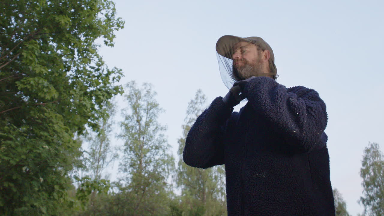 Man puts on mosquito head net to protect body against summer mosquitoes, closeup