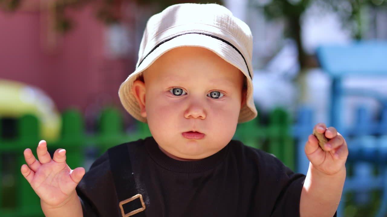 En sød lyshåret dreng leger på gaden. En tur med en baby. Børns udvikling. En dreng i T-shirt på en solrig dag. Vertikal video