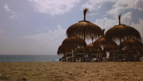 motion time lapse of marbella beach tiki umbrellas in foreground and clouds moving in background on a summer day