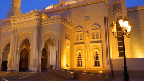 slow motion track along illuminated with golden lights mosque. lantern light at foreground. cobalt blue sky background.