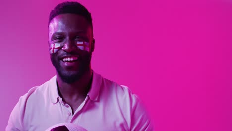 Video-of-happy-african-american-male-sport-fan-with-flags-of-england-on-neon-pink-lightning