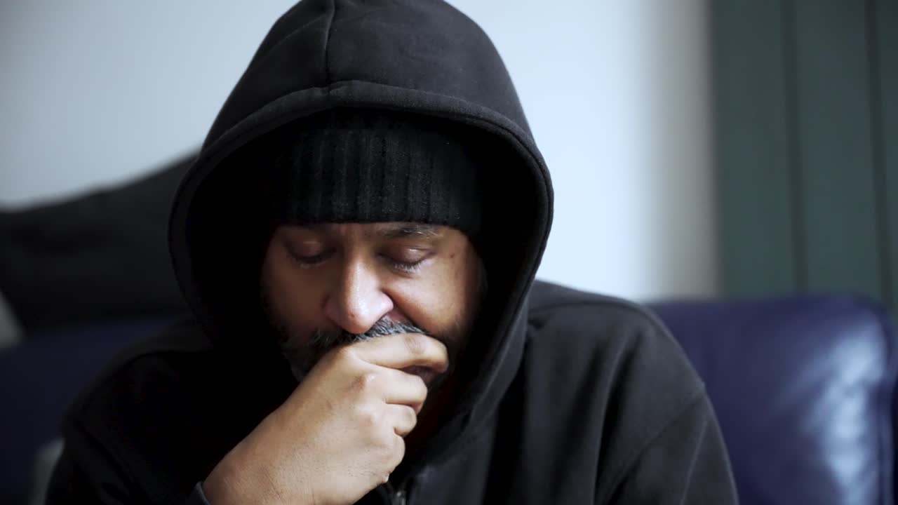 South Asian man looking worried and pensive, covering mouth with hand, reflecting on emotions