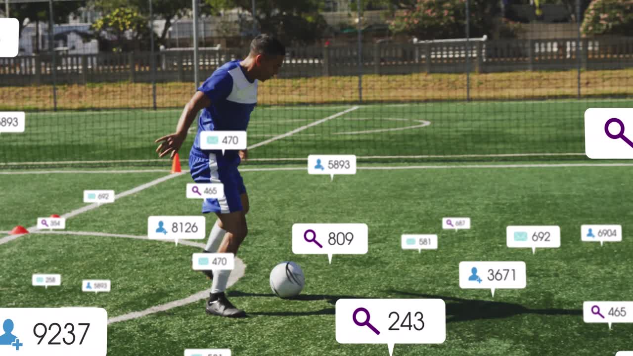 animación de iconos de las redes sociales sobre un jugador de fútbol masculino biracial practicando en un campo deportivo