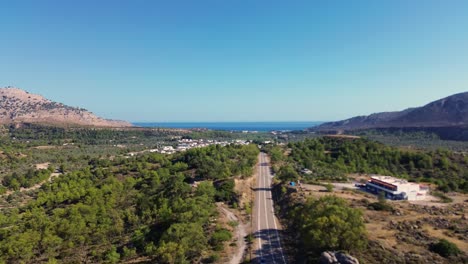 over the road and green forest in rhodes with seaside in the background in greece during the summer filmed with the drone in 4k