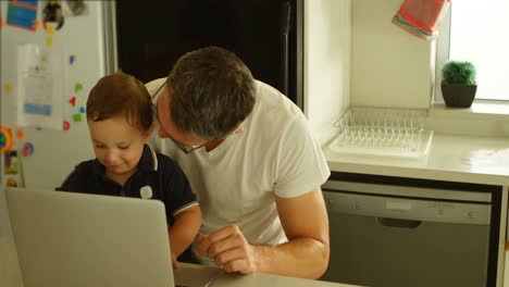 father and son using laptop in kitchen 4k